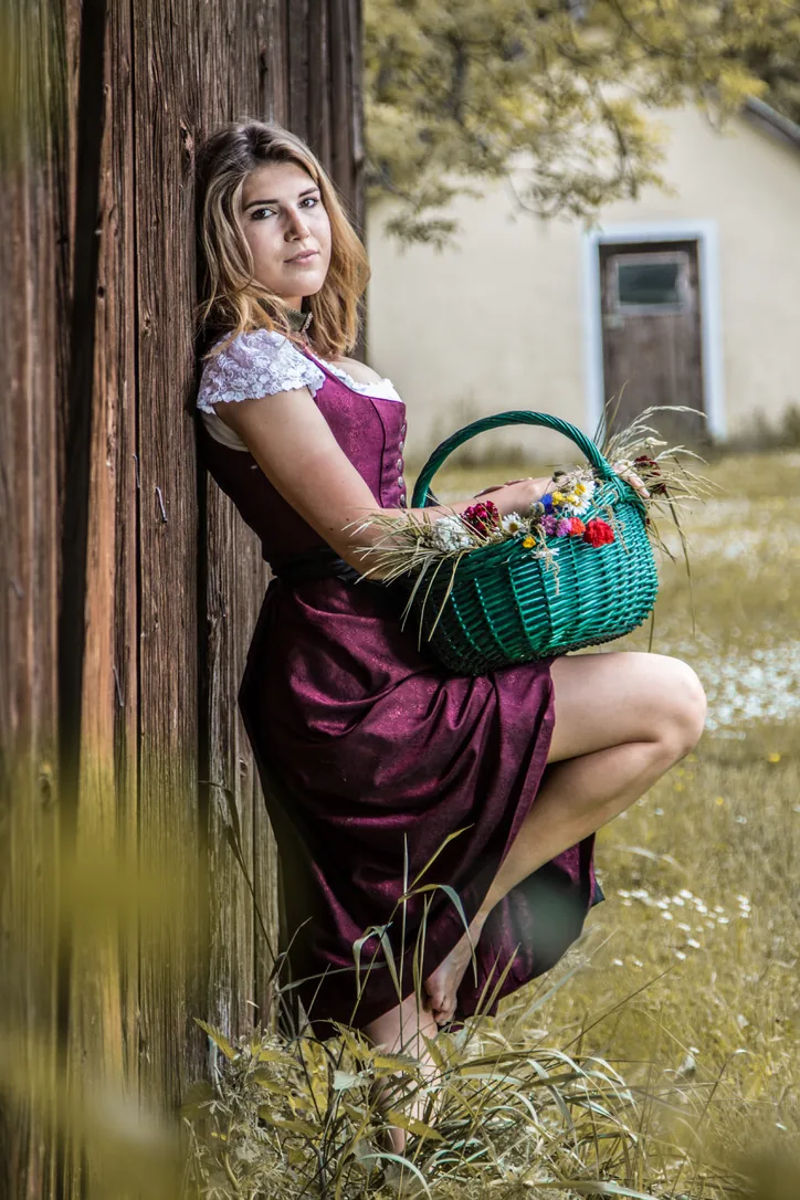 Porträt im beerenfarbenen Dirndl mit Blumenkorb